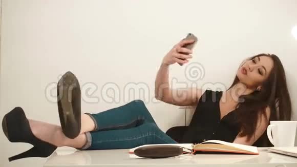 俏皮迷人的年轻女商人用手机自拍在白色背景下做鸭脸视频的预览图