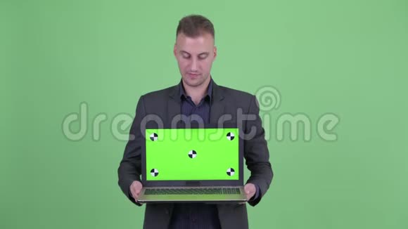 快乐英俊的商人西装革履展示笔记本电脑视频的预览图