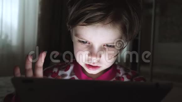 一个在黑暗中看平板电脑的可爱小女孩特写视频的预览图