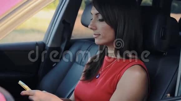迷人的年轻女性坐在车里在手机上自拍视频的预览图