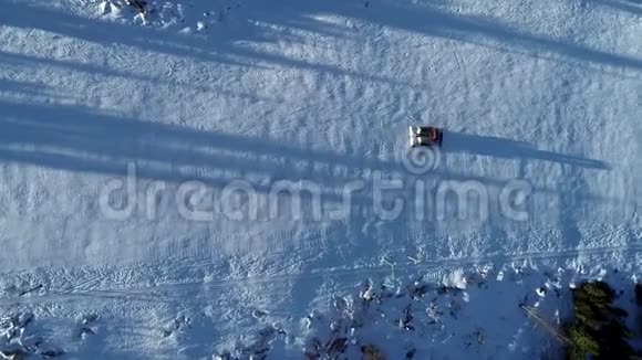 冬季滑雪场斜坡上雪猫或雪修复者的高空俯视图视频的预览图