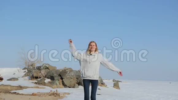 年轻女子在海滩上跳跃春天的沙滩上有雪视频的预览图