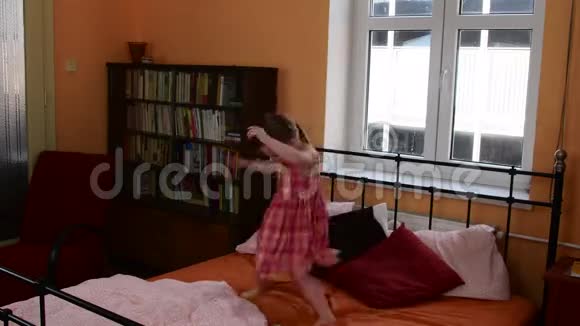 一个可爱的小女孩在床上跳父母的卧室和她的女儿正在床上跳跃视频的预览图