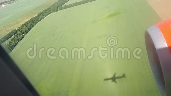 晴天的地面上飞行飞机的影子从飞机窗口观看飞机的影子在空中飞行视频的预览图