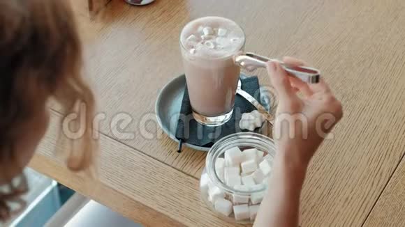 快乐的女孩喝咖啡在咖啡馆里放松微笑着看着智能手机视频的预览图