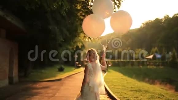美丽的微笑新娘带着气球在秋天公园散步视频的预览图