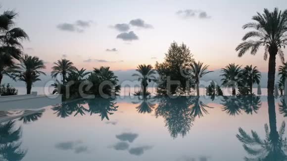 日落时度假胜地的海景游泳池和带山的大海视频的预览图