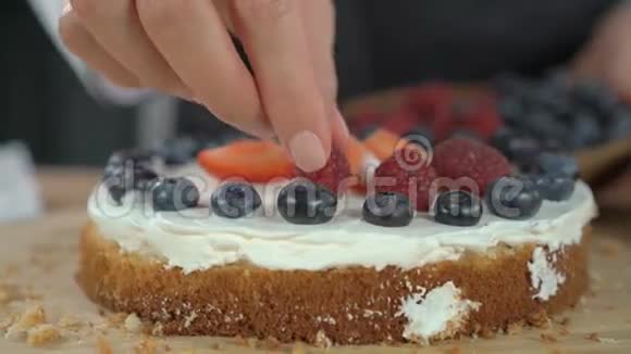 女人做浆果蛋糕用覆盆子装饰饼干视频的预览图