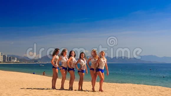 穿白色蓝色衣服的拉拉队员在海滩上表演半个特技金字塔视频的预览图