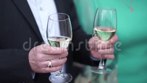 一个穿着黑色西装穿着白色衬衫的白种人手里拿着两个高杯白葡萄酒特写两副眼镜视频的预览图