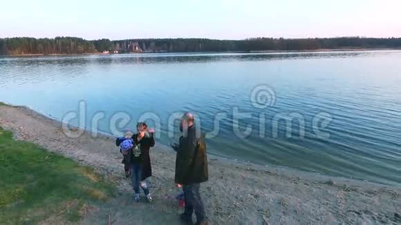 幸福的年轻家庭成员在黄昏时沿着海滩散步视频的预览图