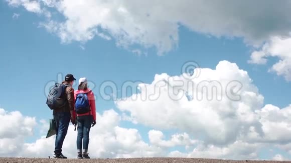 年轻迷人的旅游情侣在蓝天和白云的背景下拥抱视频的预览图