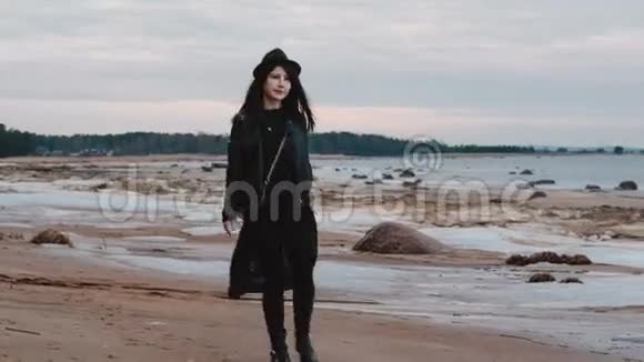 穿着黑色裙子的女孩走在海湾的岩石海岸上视频的预览图