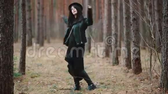 穿着黑色连衣裙和帽子的年轻女人踢树叶视频的预览图