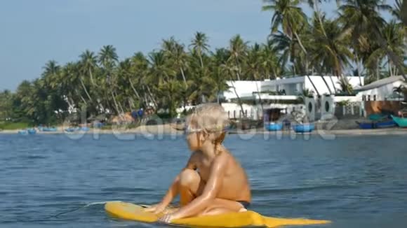 微笑可爱的孩子享受蓝海冲浪板的身体板慢动作视频的预览图