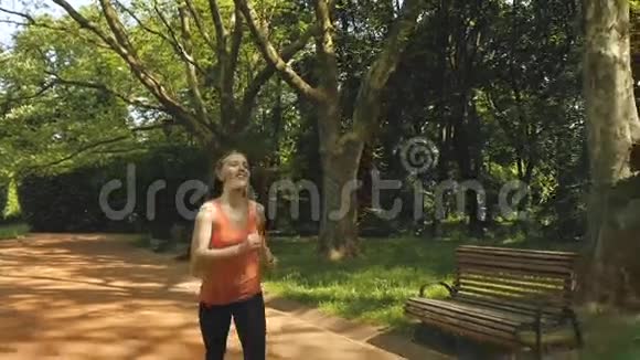 在美丽的夏日阳光下慢跑的女人在城市公园里奔跑视频的预览图