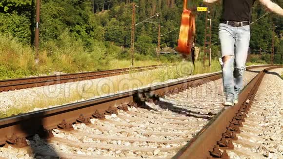 一个男少年用吉他在铁路上平衡行走视频的预览图