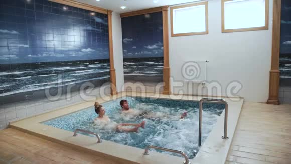 年轻夫妇正在游泳池里玩按摩浴缸泡泡放松视频的预览图