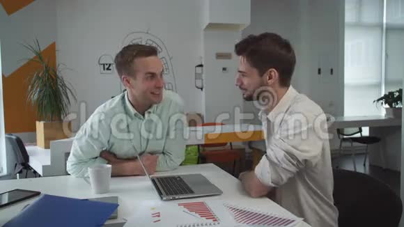 两个英俊的男人在创意时髦的办公室里进行友好的交谈视频的预览图