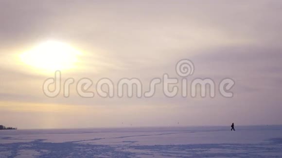 日落时分渔民在冰上行走几乎在地平线上4K视频的预览图