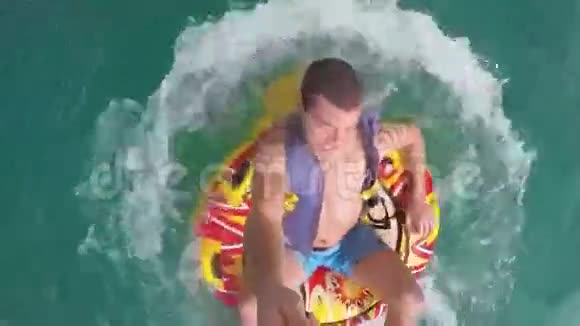 一个人坐在水中的一艘船拖着的充气环里用GoPro摄像机记录他自己视频的预览图