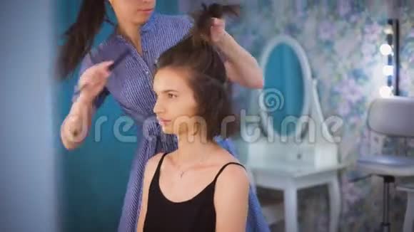 理发师梳着一个美丽的年轻黑发女郎的头发视频的预览图