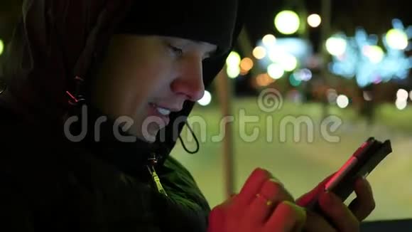 在城市的夜晚冬天的时候男人用智能手机短信特写视频的预览图