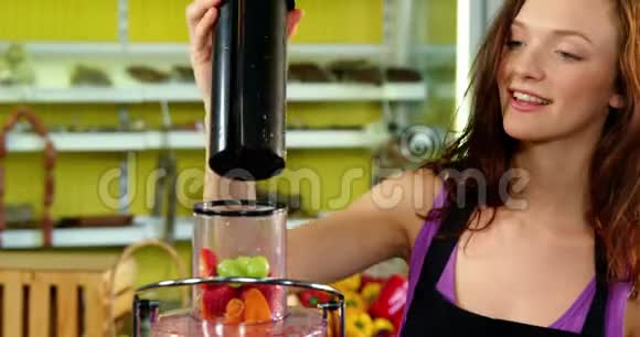在榨汁机中配制新鲜果汁的女性工作人员视频的预览图