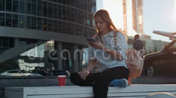 微笑女性使用智能手机语音识别的肖像年轻的白人女孩带着耳机走路视频的预览图