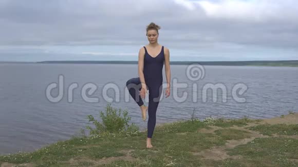 运动装瑜伽女在湖边摆姿势视频的预览图