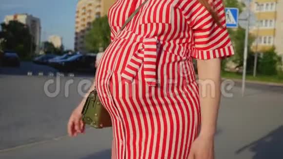 穿红色衣服的孕妇在等孩子在城里散步的女人温柔怀孕的概念视频的预览图