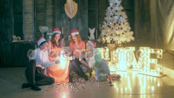一群朋友庆祝圣诞节新年玩得开心在圣诞晚会上玩闪闪发光视频的预览图