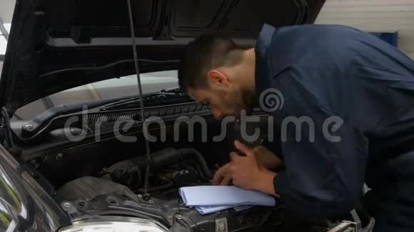 英俊的机械师检查汽车发动机里的油视频的预览图