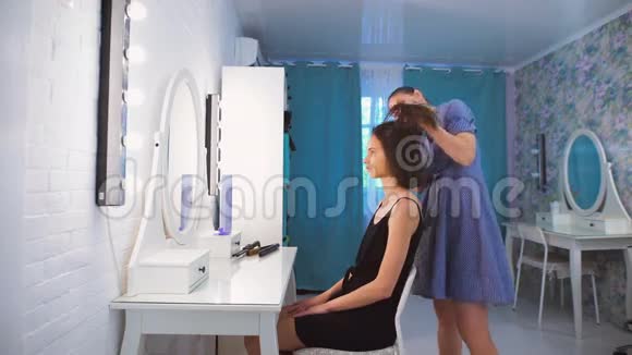 理发师梳着一个美丽的年轻黑发女郎的头发视频的预览图