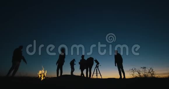 夜晚用望远镜观察篝火的朋友视频的预览图