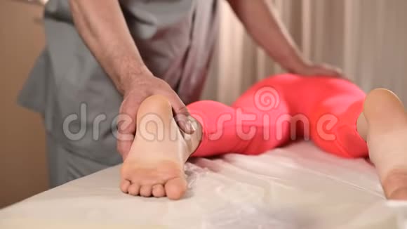 男性手动内脏治疗师按摩师治疗年轻女性患者与下背部的臀部一起工作视频的预览图