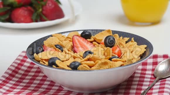 早上的早餐牛奶倒入盛有玉米片和浆果的碗中视频的预览图