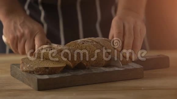 男性将自制面包切片放在木桌上视频的预览图