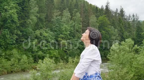 一位年长的女士在森林和山脉的外面为上臂做伸展运动视频的预览图