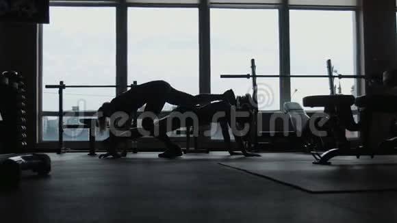 剪影两个女孩一起在健身房做俯卧撑视频的预览图