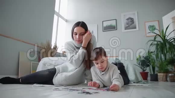 妈妈带着一个孩子在他家白色的内部和他的小儿子一起收集拼图快乐视频的预览图
