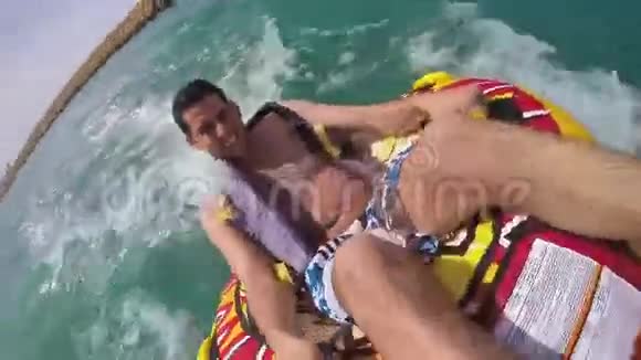 一个人坐在水中的一艘船拖着的充气环里用GoPro摄像机记录他自己视频的预览图