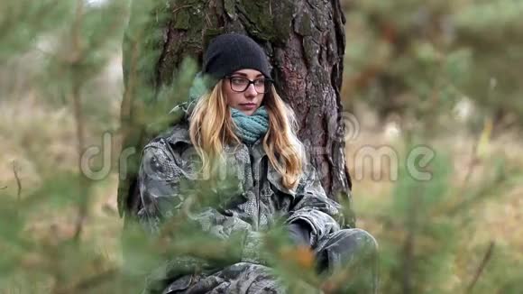秋天女孩穿着防护服坐在松树上视频的预览图