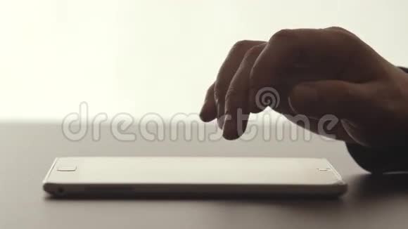 侧视图人的手在桌子上的平板电脑上用手指触摸视频的预览图