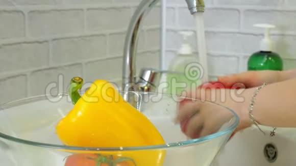 女人在厨房的水槽里的水龙头下面洗新鲜蔬菜把它们放进玻璃杯里视频的预览图