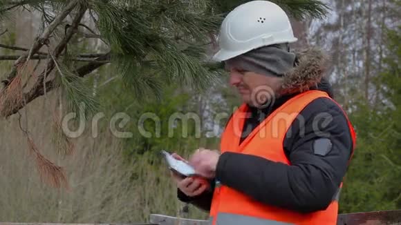 林业工人在森林里的树附近拍照视频的预览图