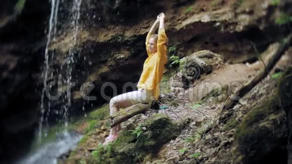 年轻女子站在瀑布前举起双手女游客张开双臂看着视频的预览图