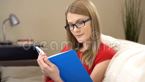 一位戴眼镜的年轻美女坐在沙发上看书视频的预览图