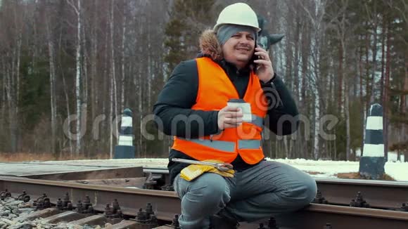 铁路上有咖啡和智能手机的铁路工人视频的预览图