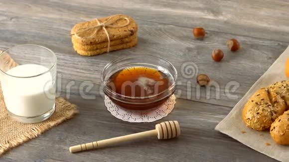 蜂蜜牛奶饼干和新鲜的小面包放在乡村的木桌上乡村早餐视频的预览图